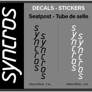 May include: A black and gray decal with the text "SYNCROS" in white. The decal also features the text "DECALS - STICKERS" and "Seatpost - Tube de selle". Two color options are shown: Glossy Black and Matte White.