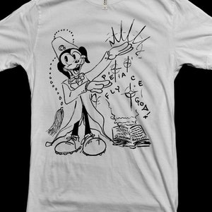 Puede incluir: Una camiseta blanca con una ilustración en blanco y negro de un personaje de dibujos animados con un sombrero y sosteniendo un libro. El texto "Peace Fly God" está escrito en un círculo alrededor del personaje.