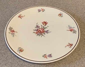May include: A white ceramic plate with a gold rim and a floral design. The flowers are pink, purple, and green.