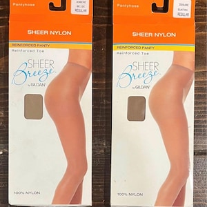May include: Two packages of sheer nylon pantyhose. The packaging is orange and white, with the words "SHEER NYLON" and "SHEER Breeze by GILDAN." The pantyhose are beige and suntan colors. The packaging also states "REINFORCED PANTY" and "Reinforced Toe."
