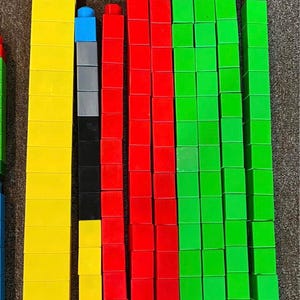 May include: A collection of colorful, rectangular building blocks in various sizes and colors, including yellow, red, green, blue, black, and purple. The blocks are arranged vertically, showcasing their different lengths and quantities.