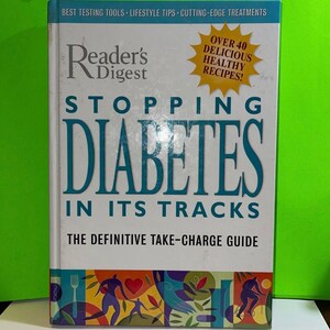 May include: A book titled "Stopping Diabetes in Its Tracks: The Definitive Take-Charge Guide" by Reader's Digest. The cover features a blue and white title with a yellow starburst graphic that says "Over 40 Delicious Healthy Recipes!"