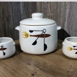 Peut inclure: Un ensemble de trois bols en céramique blanche avec un motif noir et brun d'ustensiles de cuisine. Les bols sont de tailles différentes et ont un design unique.