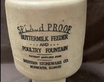 May include: A white ceramic splash-proof buttermilk feeder and poultry fountain. The feeder has black lettering that reads "Splash Proof Buttermilk Feeder... And... Poultry Fountain Patent Applied For Western Stoneware Co. Monmouth, Illinois."
