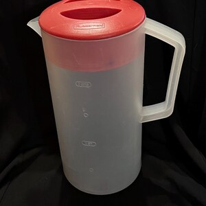 May include: A clear plastic pitcher with a red lid and handle. The pitcher has measurement markings for 1 and 2 quarts. The lid is marked with the brand name "Rubbermaid".