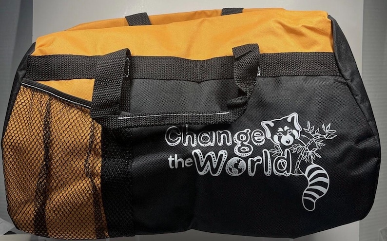 May include: A black and orange duffel bag with black handles and a side mesh pocket. The bag features the text "Change the World" with a red panda graphic.