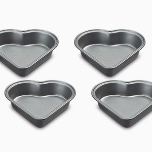 Könnte beinhalten: Set aus vier herzförmigen Backformen aus dunkelgrauem Metall. Die Formen sind zum Backen von Kuchen, Keksen oder anderen Leckereien in Herzform gedacht.