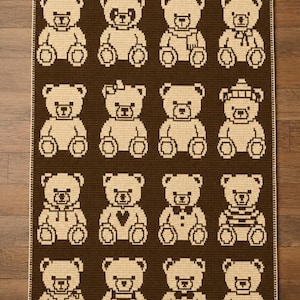 Puede incluir: Una manta de ganchillo rectangular con un patrón repetitivo de dieciséis osos de peluche dispuestos en cuatro filas de cuatro. Los osos son de color beige claro sobre un fondo marrón oscuro, cada uno con detalles únicos como lazos, sombreros o camisas.