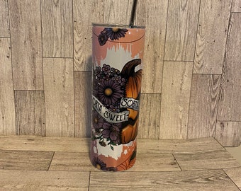 May include: A pink and white stainless steel tumbler with a floral design and a pumpkin with the text "Sorta Sweet" on it. The tumbler has a straw.