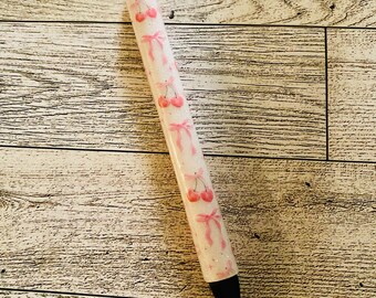 May include: A white pen with a pink glitter finish and a design of pink cherries with bows.