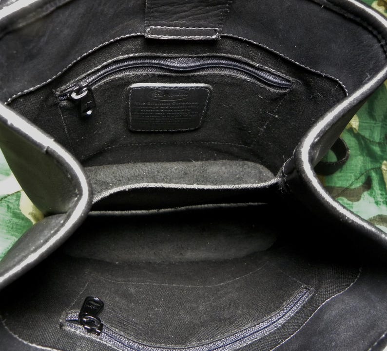 May include: Black leather handbag with multiple interior compartments and a zippered closure. The bag features a rectangular shape with a top flap and a shoulder strap. The interior includes a small leather tag.