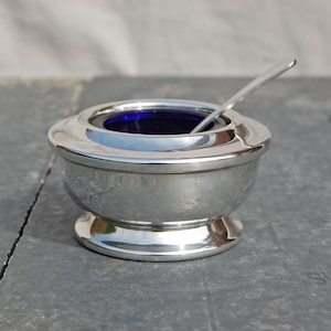 May include: Silver salt cellar with a blue glass liner and a small spoon.
