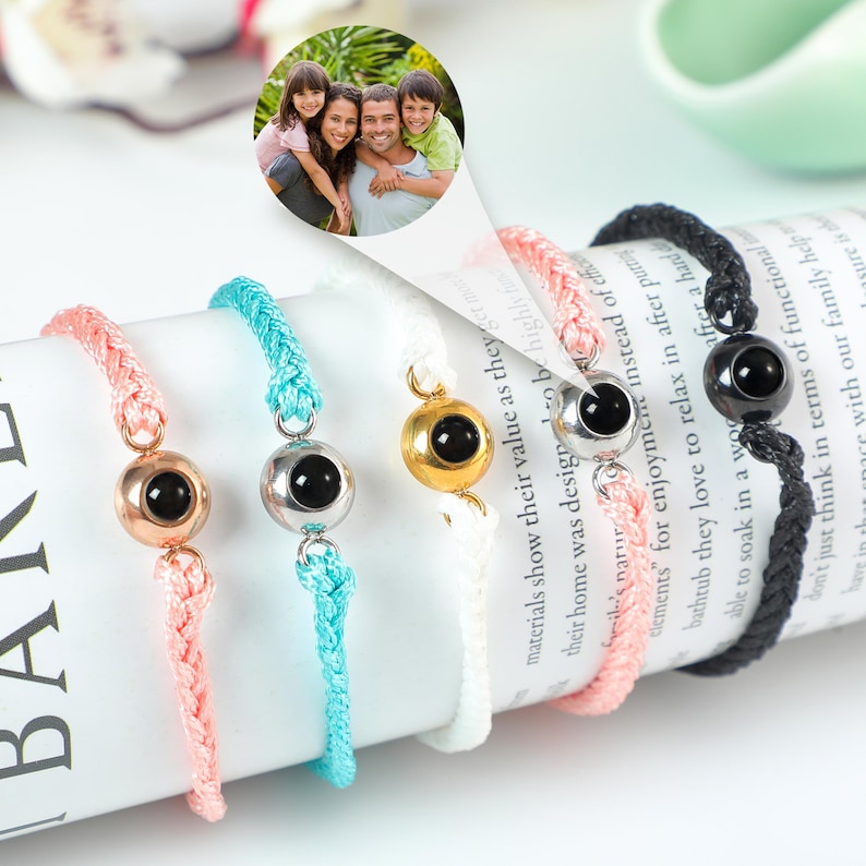 Puede incluir: Cinco pulseras trenzadas de colores vivos con un peque&ntilde;o dije redondo que contiene una foto en su interior. Los dijes son plateados, dorados, negros y dos tonos de azul diferentes.
