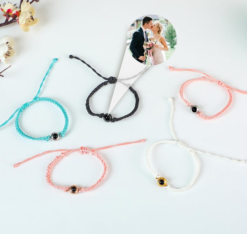Puede incluir: Cinco pulseras de amistad de colores con un peque&ntilde;o dije redondo en el centro. Los dijes son negros, dorados y plateados. Las pulseras est&aacute;n hechas de un hilo delgado y est&aacute;n atadas con un nudo.