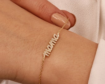 May include: A gold chain bracelet with the word "MAMA" spelled out in small diamonds.