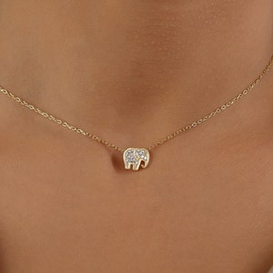 May include: A gold chain necklace with a small, diamond-encrusted elephant pendant.