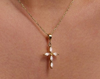 May include: A gold chain necklace with a small, clear crystal cross pendant.
