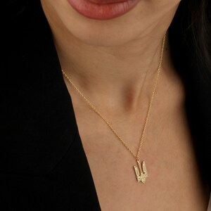 May include: A gold chain necklace with a small, detailed trident pendant. The pendant is a symbol of Ukraine.