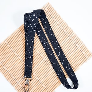 May include: Black lanyard with a white constellation pattern and silver clip.