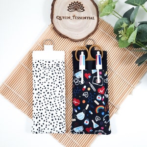May include: Two fabric pouches with zipper closures. One pouch is black with a white polka dot pattern. The other pouch is black with a colorful medical themed print. The pouch with the medical print has a pair of scissors and two pens inside.