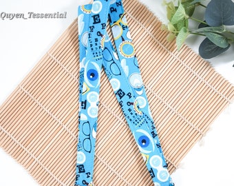 May include: A blue lanyard with a white eye chart and glasses print. The lanyard has a silver swivel clasp.