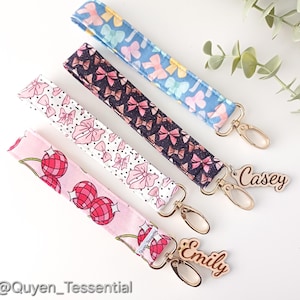 May include: Four colourful fabric keychains with gold key rings and personalised wooden tags that read "Casey" and "Emily".