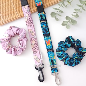 May include: Two lanyards and two scrunchies. One lanyard is light pink with a brain and bandage pattern, the other is dark blue with a brain scan pattern. The scrunchies match the lanyard patterns. Accessories.