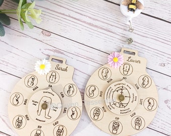 May include: Two wooden baby position reference wheels with a flower and a bee charm. The wheels are labeled "Sarah" and "Laurer" and show different baby positions in the womb.