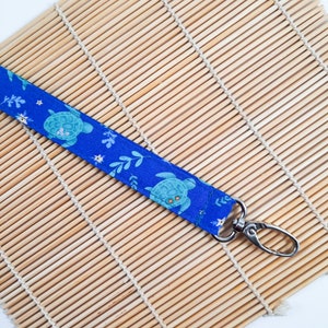 May include: A blue fabric key chain with a sea turtle pattern and a silver swivel clasp.