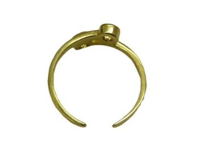 Pu&ograve; includere: Un anello color oro con un design aperto. L'anello ha una fascia arrotondata che si curva, con un piccolo dettaglio circolare rialzato in alto. L'anello &egrave; realizzato in un materiale metallico lucido.