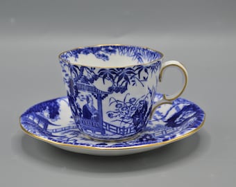 May include: A blue and white porcelain teacup and saucer set with a gold trim. The set features a Japanese-inspired design with a scene of a woman in a garden.