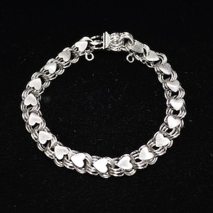 May include: Silver-toned bracelet featuring a series of heart-shaped links. The bracelet has a double-strand design, with each heart link connected to the next. The clasp is a simple hook and eye closure. The bracelet is displayed against a black background.