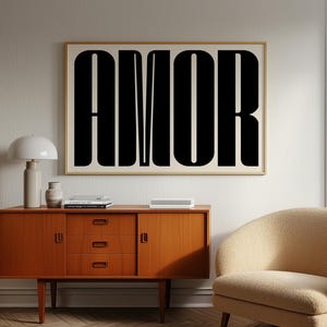 May include: A framed print featuring the word "AMOR" in large, black letters. The artwork is displayed above a wooden cabinet. A beige armchair and a white lamp are also visible in the room.