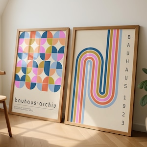 Peut inclure: Deux affiches encadrées de style Bauhaus. L'une présente un motif géométrique de demi-cercles colorés. L'autre a un design incurvé et rayé en bleu, orange, rose et jaune. Les cadres sont de couleur marron clair.