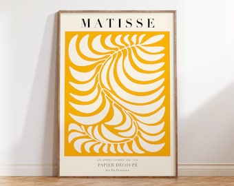 以下が含まれることがあります： 黒色の「MATISSE」という名前が書かれた額入りのアートプリント。アートワークは、明るい黄色の背景に白い葉のようなデザインが特徴です。プリントの下部にはフランス語のテキストが含まれています。