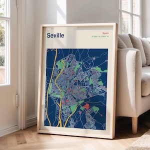 Puede incluir: Un mapa enmarcado de Sevilla, España, con un diseño detallado de la ciudad en azul, verde y rojo. La impresión incluye el nombre de la ciudad y las coordenadas geográficas. El marco es de color madera clara.