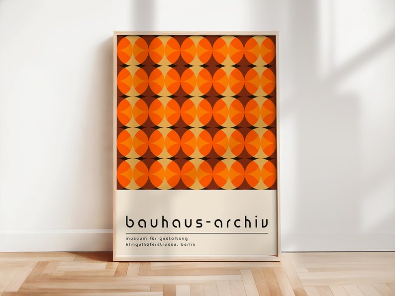 May include: A framed poster with a geometric pattern of orange and brown circles. The poster has the text "bauhaus-archiv" in black letters, followed by "museum f&uuml;r gestaltung" and "klingelh&ouml;ferstrasse, berlin" in smaller black letters.