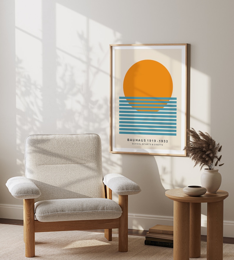 May include: A framed print with a minimalist geometric design featuring a large orange circle over a series of blue and teal horizontal lines. The text "BAUHAUS 1919 - 1933 SCHOOL OF ARTS & CRAFTS" is printed below the design.
