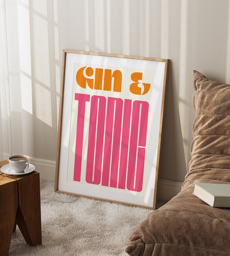 May include: A framed print with the text "Gin & Tonic" in a retro, bold font. The text is in orange and pink on a white background.