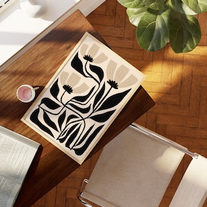 May include: A framed print with a minimalist design featuring stylized black leaves and beige flowers on a cream background.