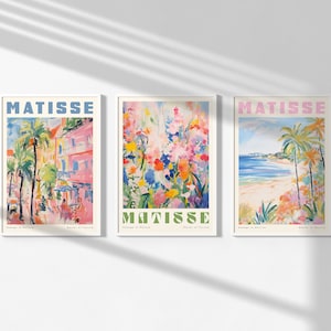 May include: Three framed art prints with the word "MATISSE" in pink and green letters. The prints feature colorful abstract paintings of flowers, a beach scene, and a street scene.