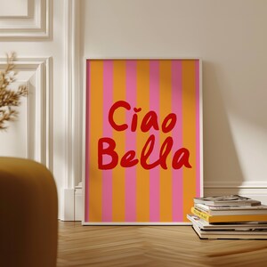 May include: A framed print with a pink and orange striped background and the text "Ciao Bella" in red.