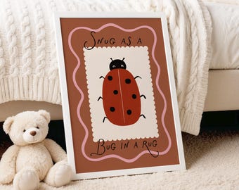 Puede incluir: Un cuadro enmarcado con una ilustración de una mariquita de dibujos animados y el texto "Snug as a Bug in a Rug". La mariquita roja con lunares negros y cabeza negra está sobre un fondo crema con un borde rosa. El marco es blanco.