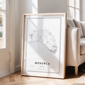 Könnte beinhalten: Gerahmter Druck einer schwarz-weißen Karte von Menorca, Spanien. Der Druck befindet sich in einem hellen Holzrahmen und lehnt an einer Wand. Der Text "MENORCA SPAIN" ist unten aufgedruckt.