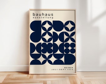 May include: A poster with a geometric design in navy blue and cream. The poster reads "bauhaus ausstellung WEIMAR JULI-SEPT 1923".