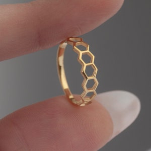 Peut inclure: Une bague dorée avec un motif en nid d'abeille. La bague est en métal et présente un motif délicat et ajouré.