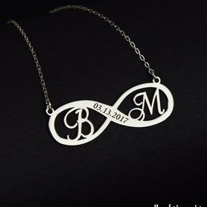 Könnte beinhalten: Silberne Unendlichkeitskette mit zwei Initialen, "B" und "M", und dem eingravierten Datum "03.13.2017" auf dem Anhänger.