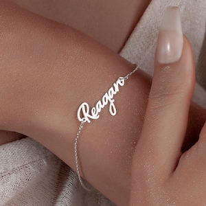 May include: A silver bracelet with the name "Reagan" written in cursive.
