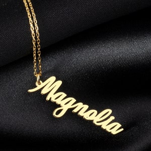 May include: A gold necklace with a cursive name pendant that reads "Magnolia".