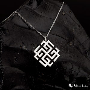 May include: A silver chain necklace with a square pendant featuring a geometric knot design. The pendant is made of silver and has a polished finish.